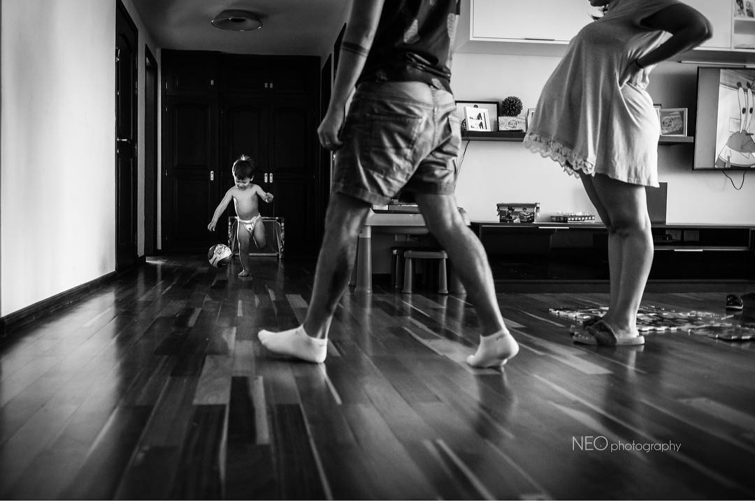 Niño jugando a la pelota en casa con sus padres, en blanco y negro