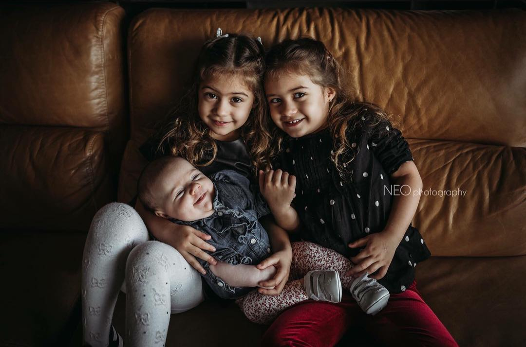 Tres hermanos abrazados en el sofá
