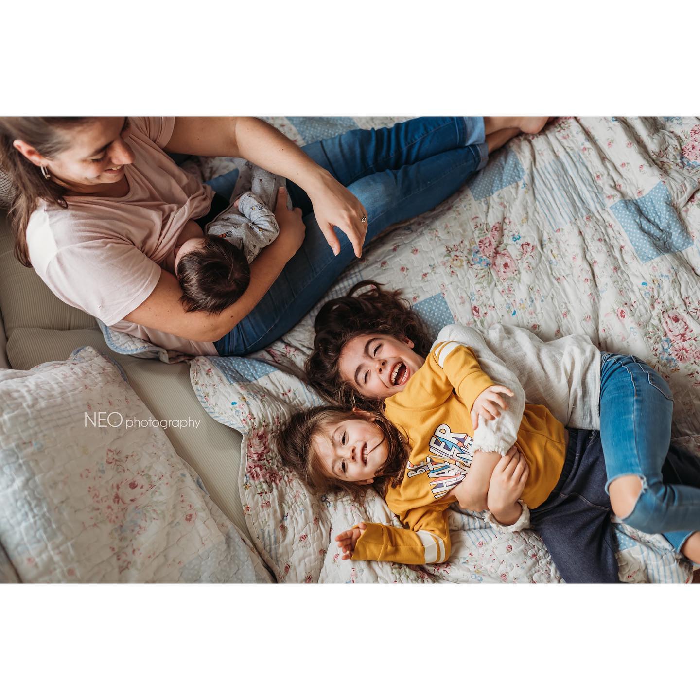 Mamá y sus hijos riendo juntos en la cama