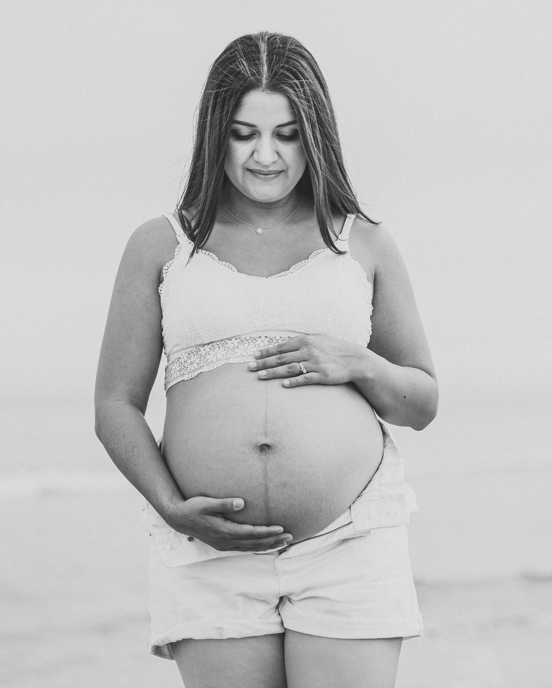 Retrato en blanco y negro de una mamá abrazando su panza