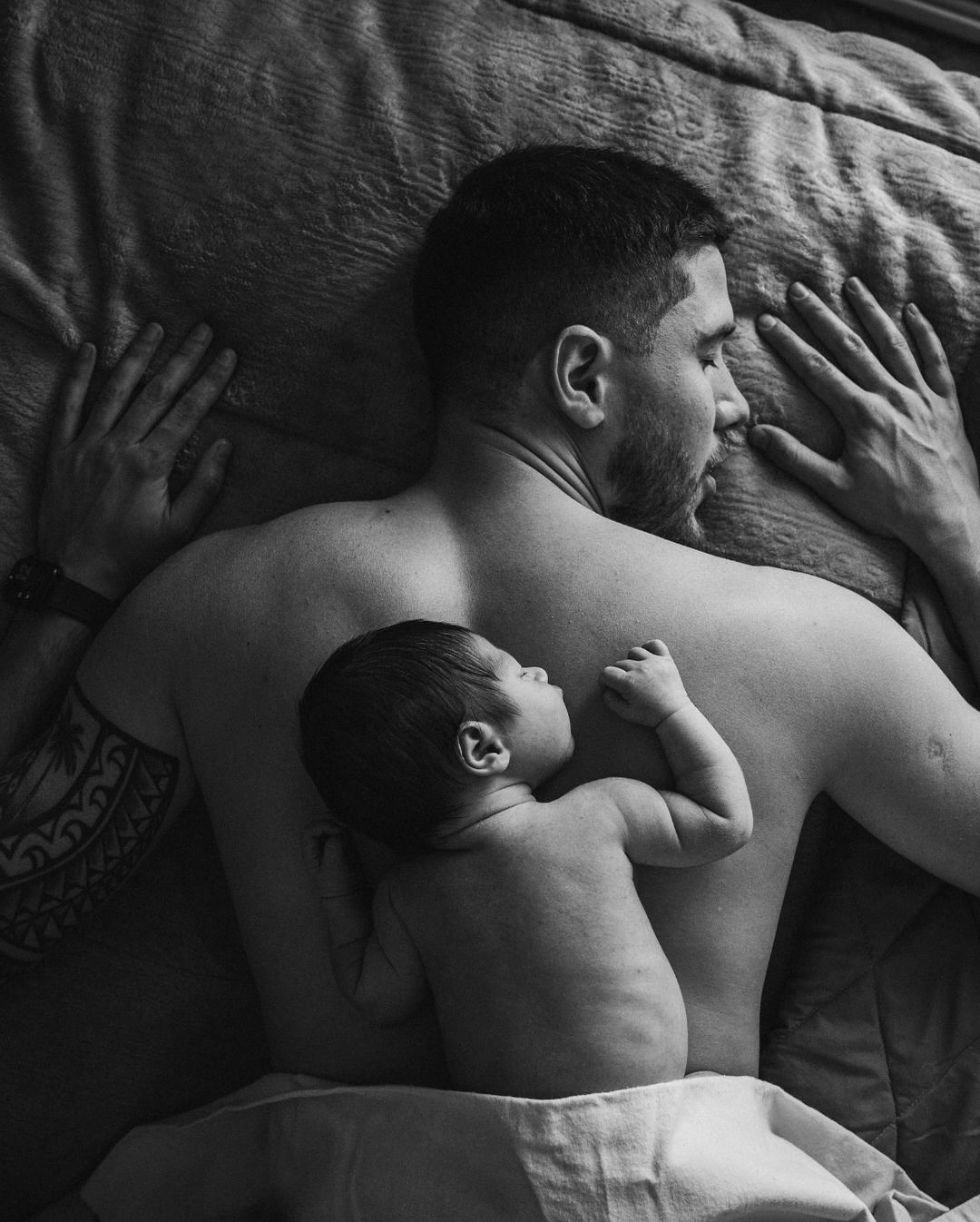 Bebé recién nacido durmiendo sobre la espalda de su padre, en blanco y negro